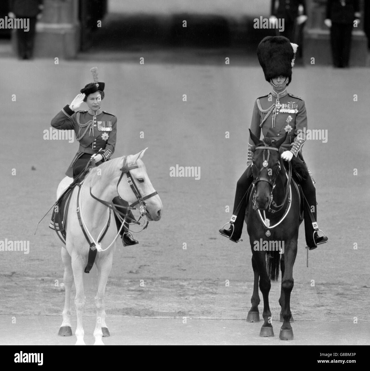 La reine Elizabeth II, avec le prince Philip, duc d'Édimbourg, saluant alors que les gardes défilent devant le palais de Buckingham après la cérémonie de Trooping de la couleur sur la parade des gardes à cheval.Les deux supports sont des chevaux de police métropolitaine.La Reine est sur le Docteur et le Duc est sur Neill. Banque D'Images
