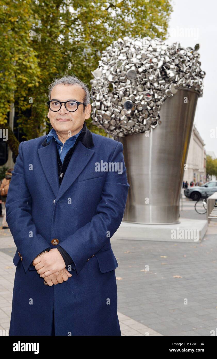 L'artiste indien contemporain Subodh Gupta se trouve devant sa dernière installation, « quand Soak devient un déversement », un seau en acier inoxydable de six mètres de haut qui déborde de centaines de casseroles, poêles et récipients de cuisson, qui se trouve à l'extérieur du Victoria and Albert Museum de Kensington, Londres. Banque D'Images