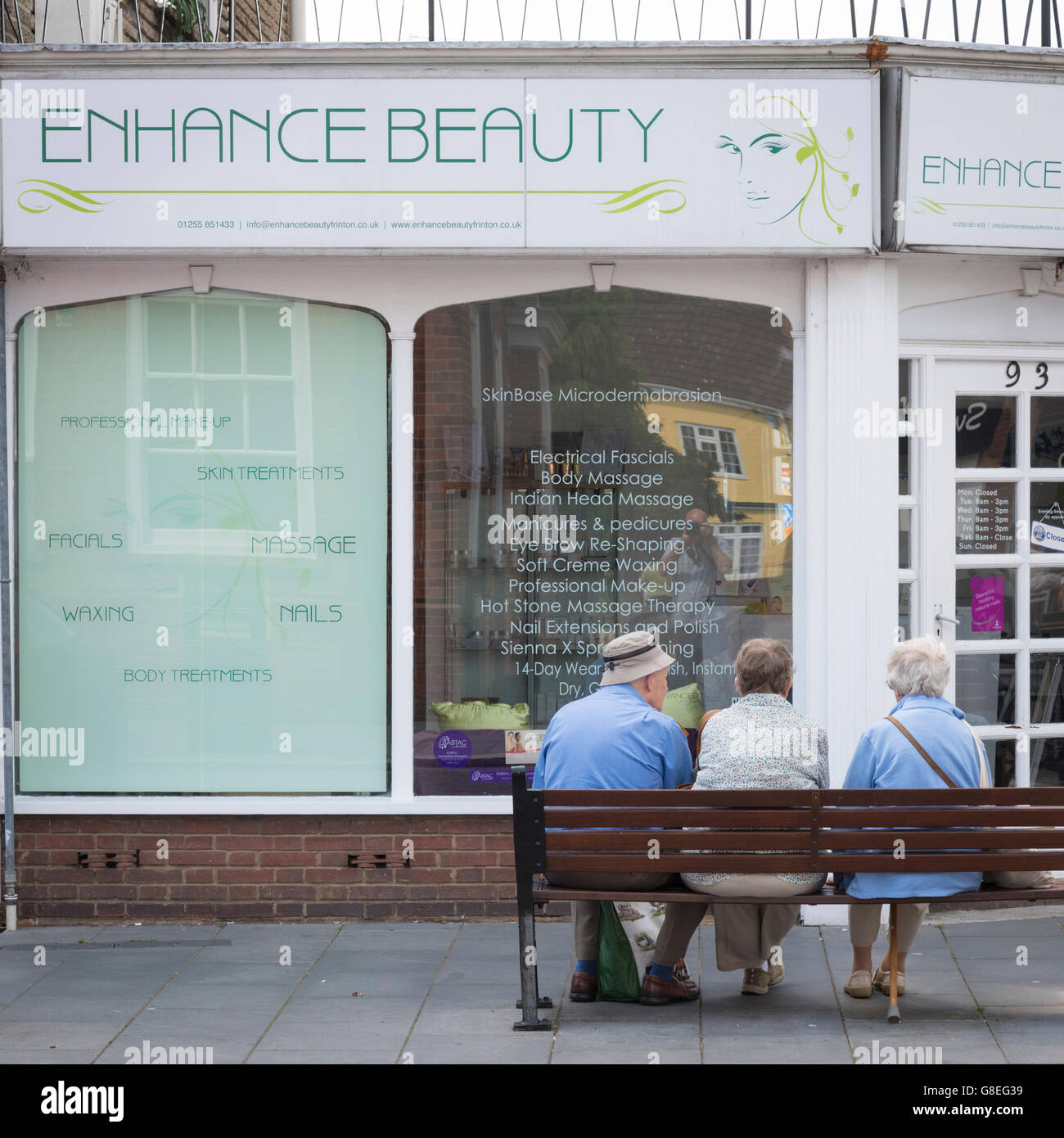 Trois personnes âgées assises sur un banc à l'extérieur d'un salon de beauté à Clacton UK Banque D'Images