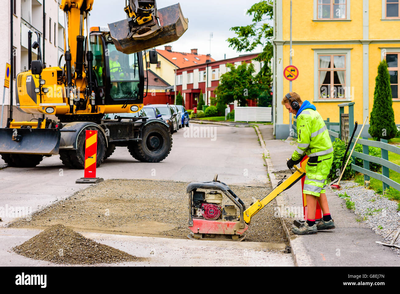 Soderkoping, Suède - 20 juin 2016 : les jeunes adultes de sexe masculin qui travaille une Honda GX200 compacteur plaque réversible sur un site de travaux Banque D'Images