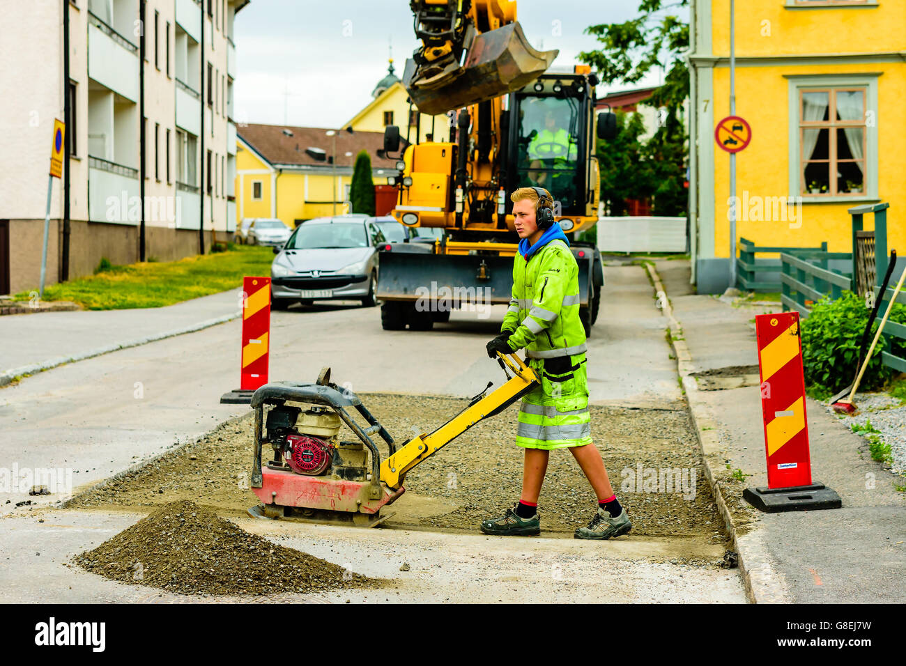 Soderkoping, Suède - 20 juin 2016 : les jeunes adultes de sexe masculin qui travaille une Honda GX200 compacteur plaque réversible sur un site de travaux Banque D'Images