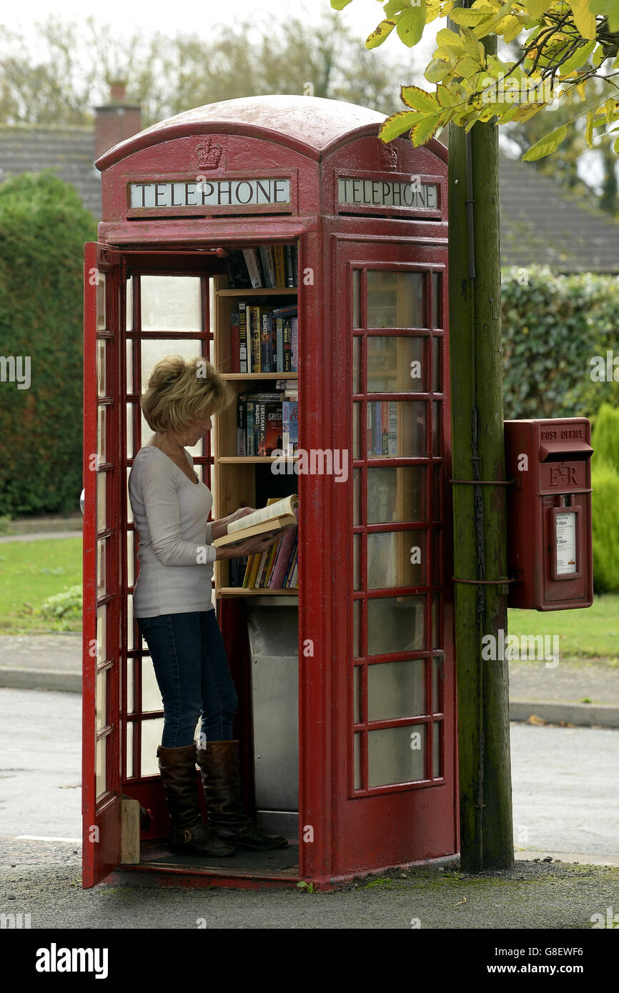 Wendy Hanlon regarde des livres dans une boîte téléphonique rouge qui a été convertie en une minuscule bibliothèque libre d'utilisation dans le village de Wall, dans le Staffordshire. Banque D'Images