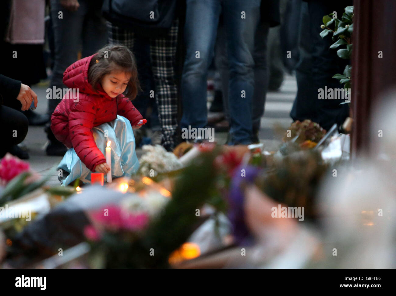 Une jeune fille laisse une bougie allumée devant le bar le Carillon, à  Paris, l'un des lieux des attaques dans la capitale française qui sont  redoutées d'avoir tué environ 127 personnes Photo