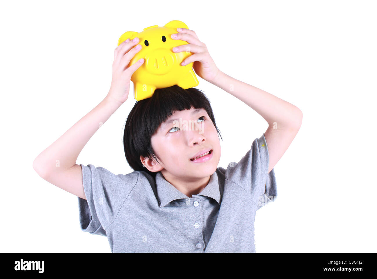 Young boy holding piggy bank jaune isolé sur blanc. Banque D'Images