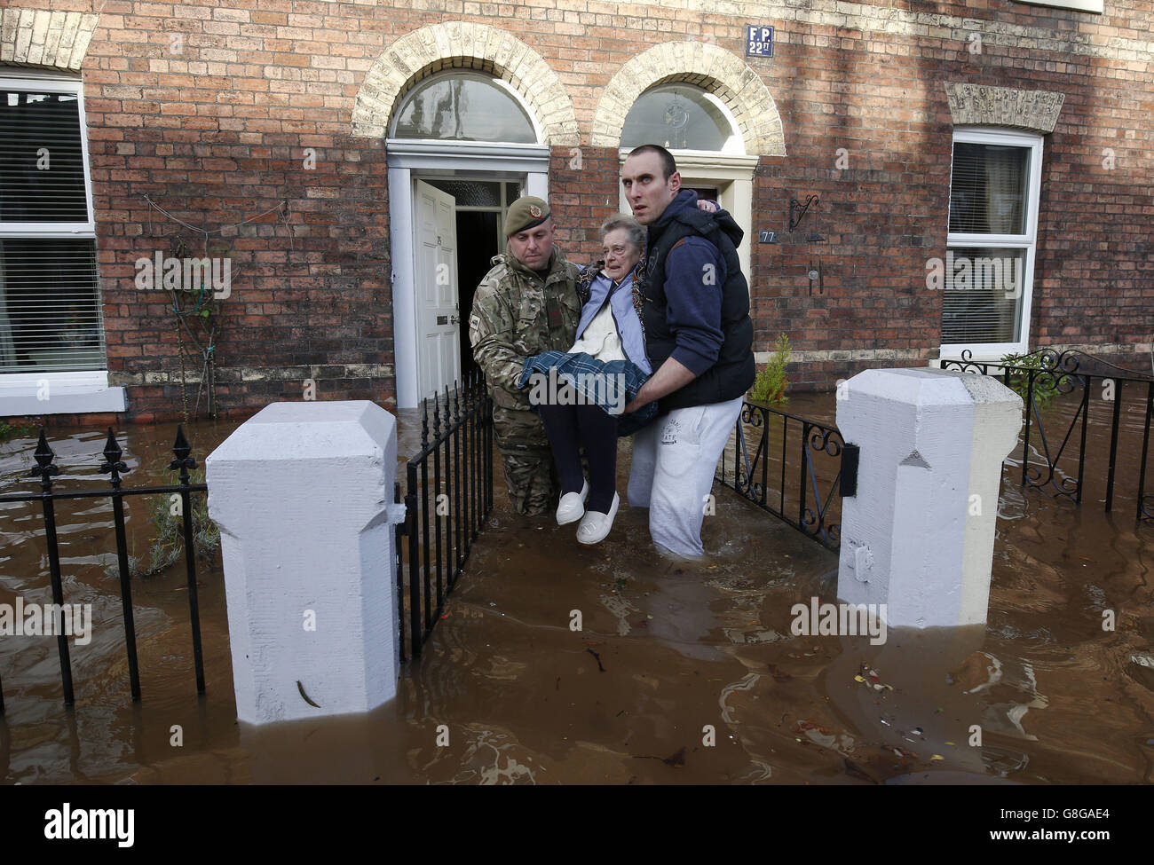 Margaret McCraken, 79 ans, est aidée de son domicile à Broad Street, à Carlisle, par les inondations des membres des forces armées qui ont été appelés pour aider à évacuer les personnes qui souhaitent déménager. Banque D'Images