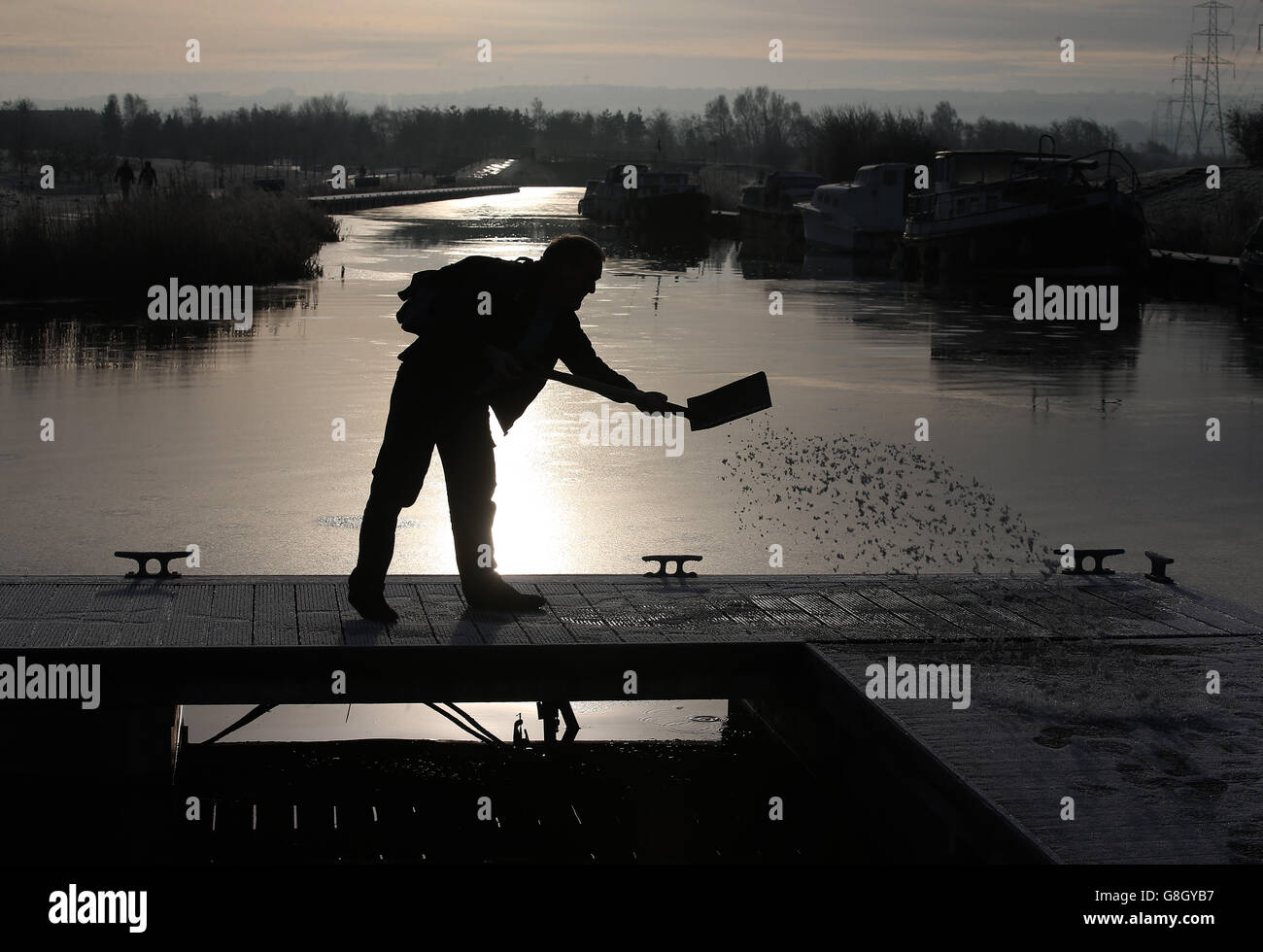 Un homme répand des grains sur des pontons le long du Forth et du canal de Clyde aux Kelpies près de Falkirk, après de fortes gelées de nuit dans le centre de l'Écosse. Banque D'Images