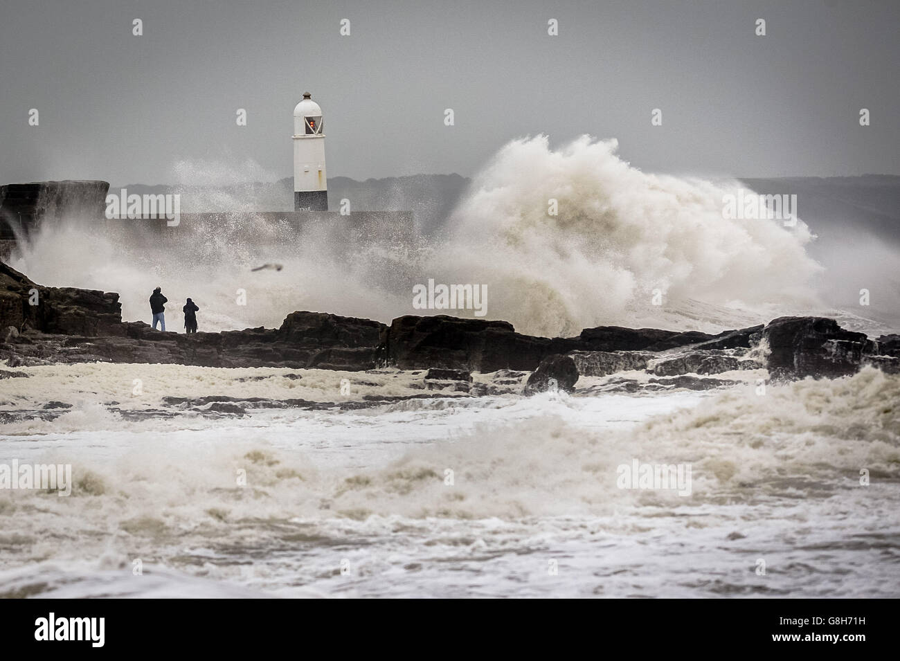 Les gens regardent les vagues près du mur du port de Porthcawl, au sud du pays de Galles, alors que Storm Desmond frappe le Royaume-Uni. Banque D'Images
