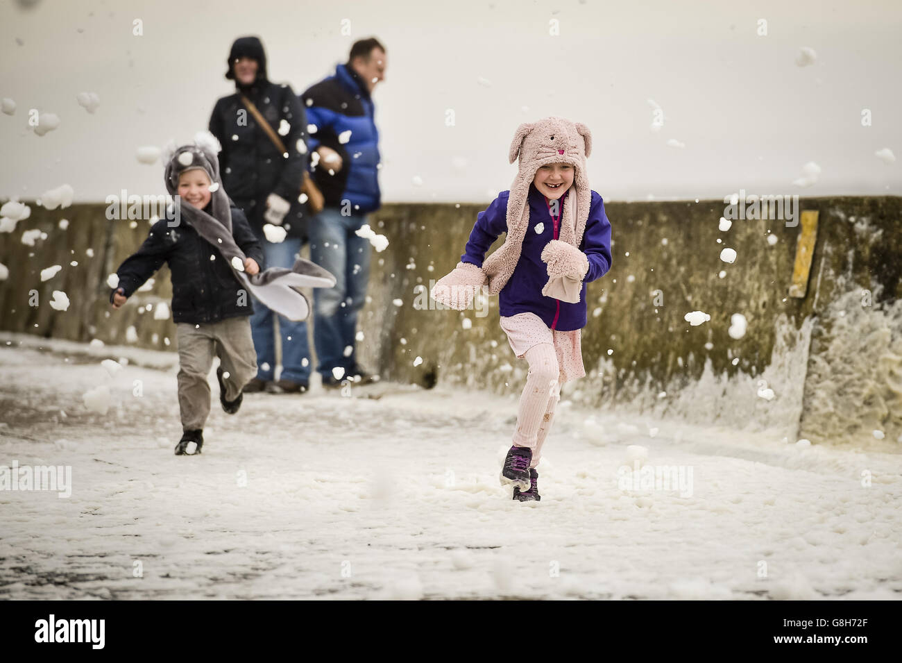 Geneviève, six ans, et son frère, Tobi, quatre ans, sont partis, ont traversé des vagues qui s'écrasant près du mur du port de Porthcawl, au sud du pays de Galles, alors que Storm Desmond a frappé le Royaume-Uni. Banque D'Images