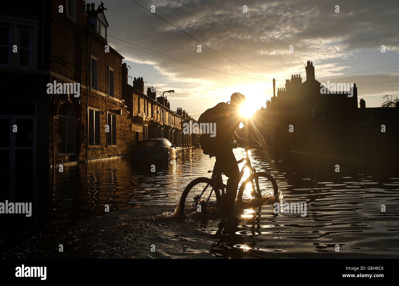 Un homme descend en vélo dans les eaux d'inondation de Eldred Street, Carlisle. Banque D'Images
