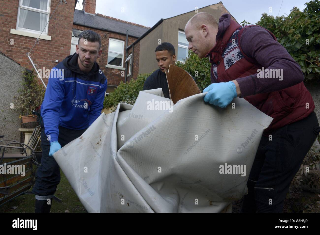Les footballeurs Carlisle United (de gauche à droite) Michael Raynes, Joe Thompson et Jason Kennedy aident à éliminer les objets d'une maison inondée de Carlisle, alors que les joueurs du club ont offert de l'aide aux personnes touchées par Storm Desmond. Banque D'Images