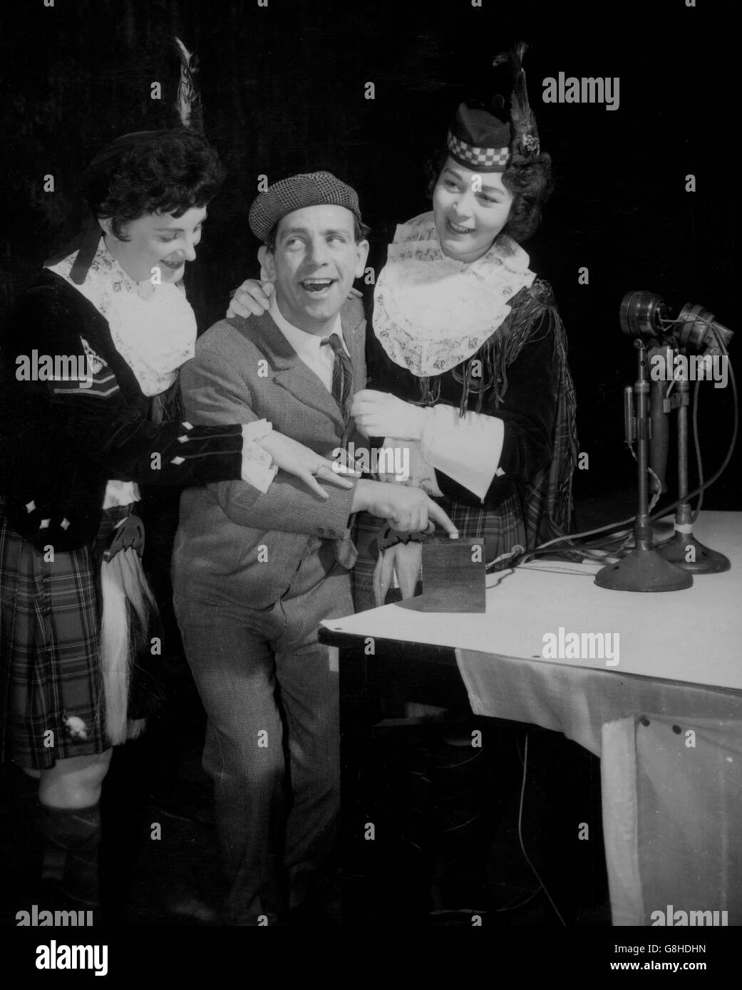 Le comédien Norman Wisdom est aidé par deux membres des Dagenham Girl Pipers - le Caporal Joan Lee (l) de 21 ans et le Major du tambour Ann Bechellier - alors qu'il commence le tirage au sort de la 7e prime Bonds par contrôle à distance au cinéma Odeon, Oxford Street, Manchester.Lorsque Norman Wisdom a appuyé sur le bouton, 'Ernie', le sélecteur de robot électronique, est entré en action au bureau des obligations Premium à Lytham St Annes, Lancashire, pour choisir les gagnants de 6,995 prix.*Neg est corrompu.Numérisé à partir du contact. Banque D'Images
