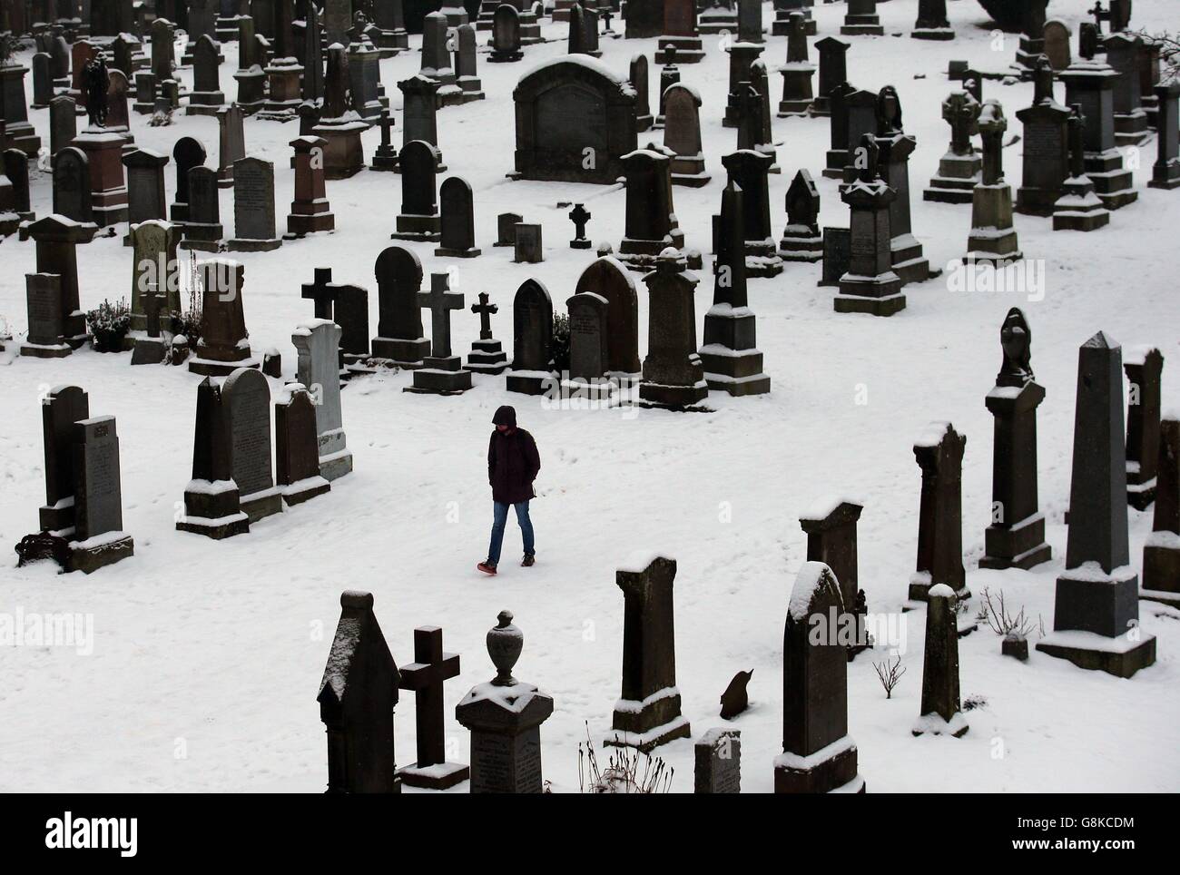 Une personne marche à travers le cimetière de l'église du Saint-rude à Stirling, l'église où Jacques VI, fils de Marie-Reine d'Écosse, a été couronné en 1567, alors que la marche à pied que la neige couvre encore le sol. Banque D'Images