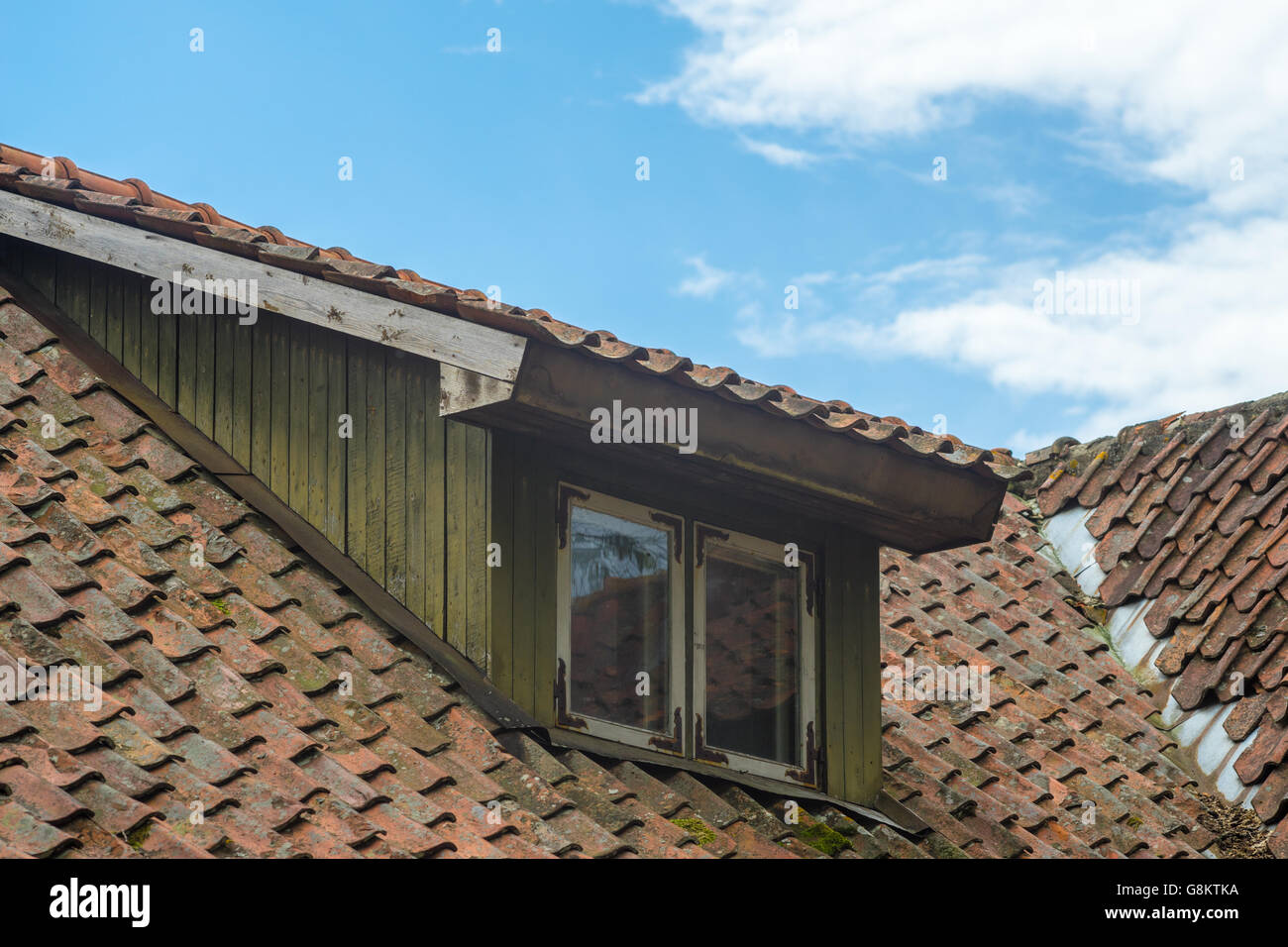 Fenêtre en mansarde à toit de tuiles anciennes contre le ciel bleu Banque D'Images