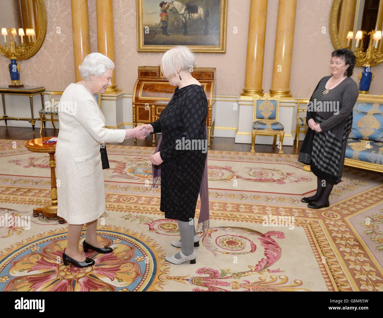 La reine Elizabeth II serre la main avec Liz Lochhead avant de lui présenter la Médaille d'or de la reine pour la poésie, accompagnée de la professeure Dame Carol Ann Duffy, poète lauréate, lors d'un audience privée, au Palais de Buckingham, dans le centre de Londres. Banque D'Images