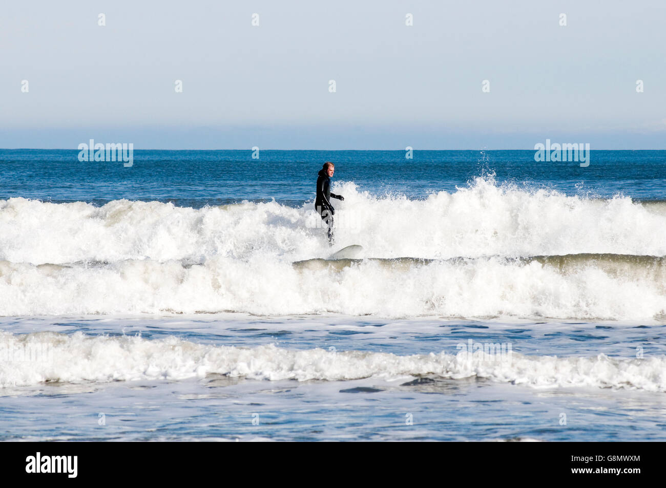 Surf homme près de Scarborough dans le Yorkshire du nord surf surfeur surf mer vagues vagues chevaux blancs beach de néoprène wetsuits combinaison sui Banque D'Images