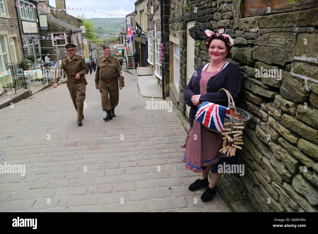 Une femme habillé en costume sourit comme deux hommes vêtus d'uniformes de la garde à domicile à pied passé au cours de l'assemblée annuelle 1940 événement à Haworth. Banque D'Images