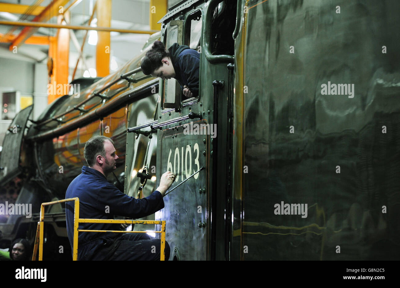 Mike O'Connor, peintre du patrimoine, peint dans le numéro du moteur sur la nouvelle décoration verte du Flying Scotsman observé par sa fille, Teriann, 21 ans, L'OMS travaille également sur la locomotive en tant que peintre du patrimoine, avant son retour officiel à la vapeur la semaine prochaine, dans un atelier au Musée national des chemins de fer à York. Banque D'Images