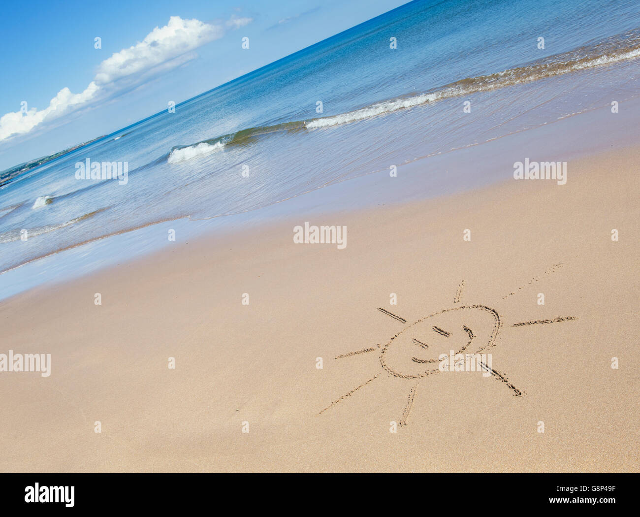 Smiley soleil de face dessin sur une plage. UK Banque D'Images