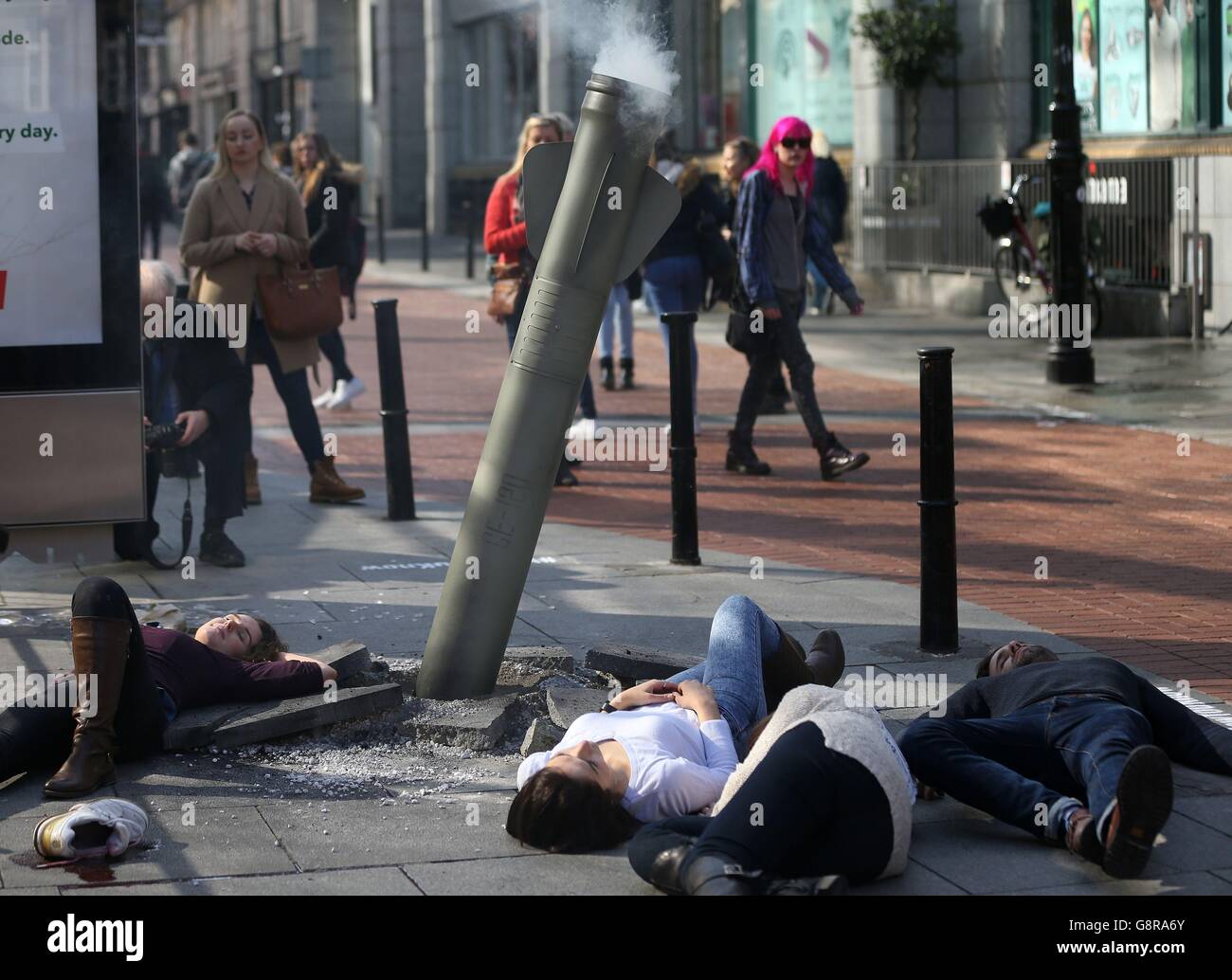 Les membres du public regardent une installation de fausse fusée dans le centre-ville de Dublin, construite à partir de matériaux récupérés, Par l'artiste de rue will St. Ledger au nom de l'agence d'aide OBJECTIF de marquer le cinquième anniversaire de la crise syrienne et de rappeler aux spectateurs que neuf enfants sont tués chaque jour en Syrie. Banque D'Images