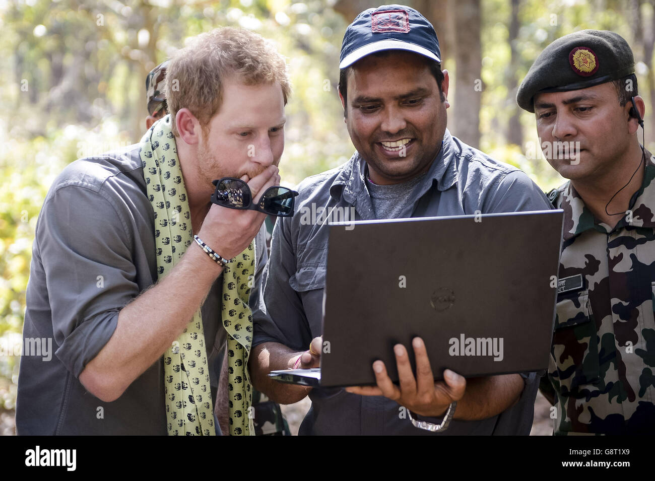 Le prince Harry regarde les photos de lui-même rampant comme un tigre, qui ont été prises par un piège à caméra au parc national de Bardia, au Népal, après avoir été invité à ramper comme l'animal pour activer le piège par l'expert de la faune Shailendra Kumar Yadar, photographié à côté de Harry, qui photographie tout ce qui bouge a passé. Banque D'Images