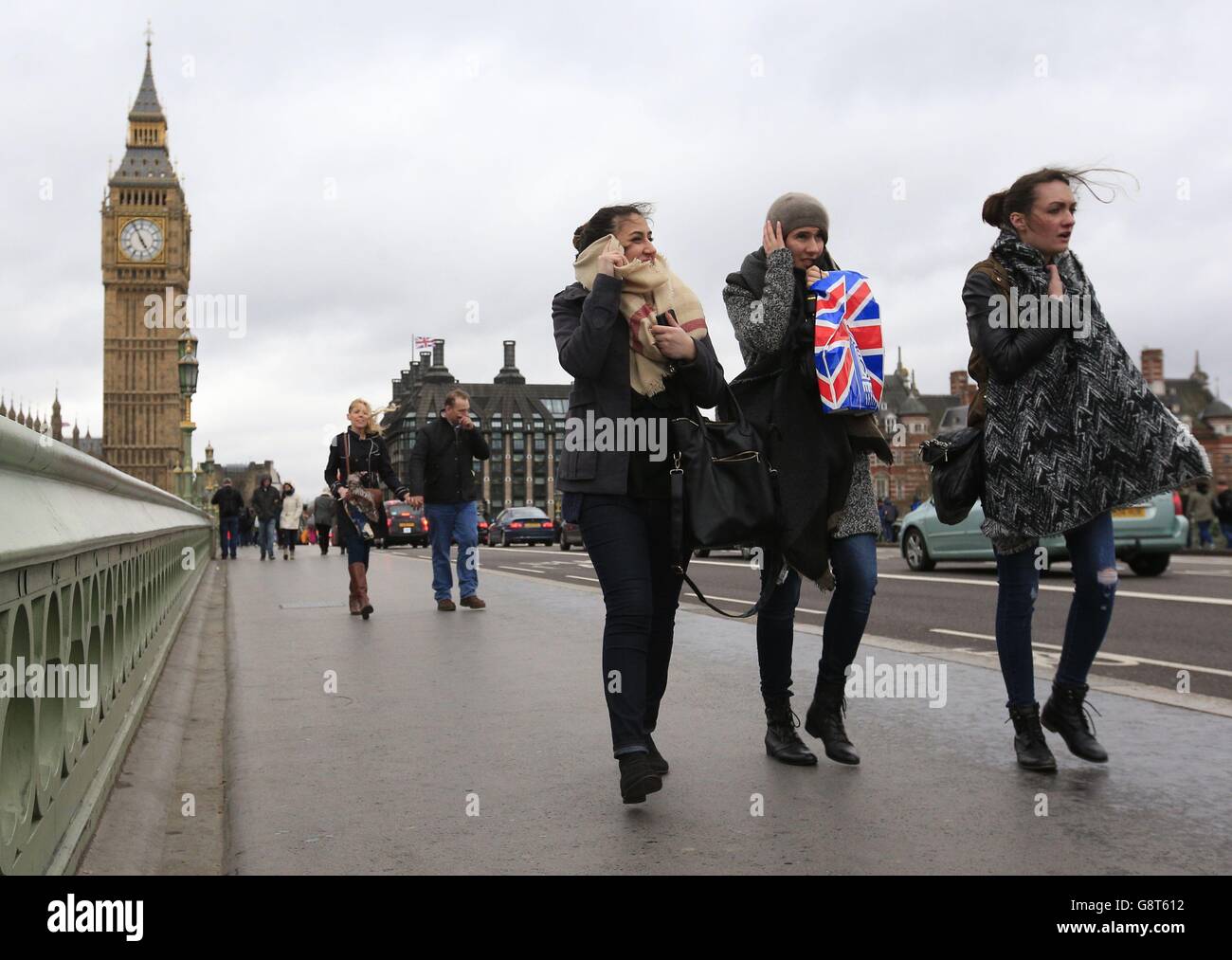 Les visiteurs du pont de Westminster, Londres, se battent contre les vents violents. La Grande-Bretagne est sur le point d'être battue par une tempête qui va provoquer de forts vents et la menace de perturbations à la fin du week-end de Pâques. Banque D'Images