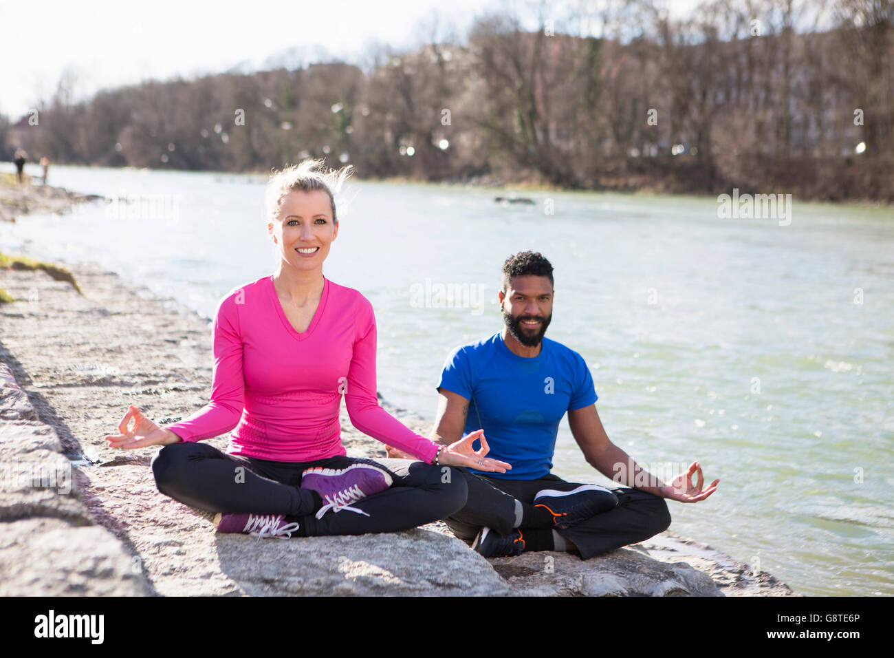 Jeune couple practicing yoga par le Riverside Banque D'Images