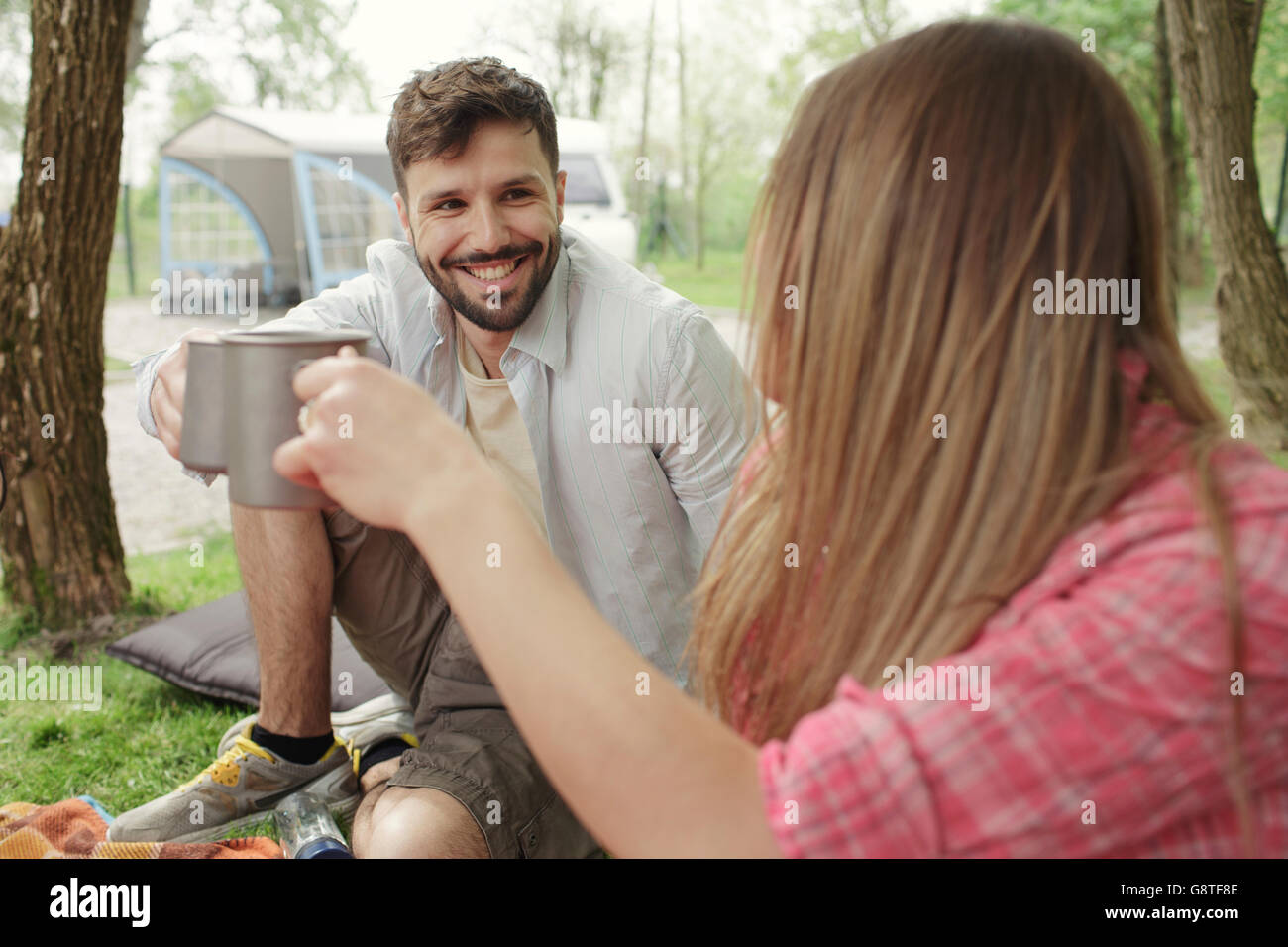Jeune couple drinking coffee at campsite Banque D'Images