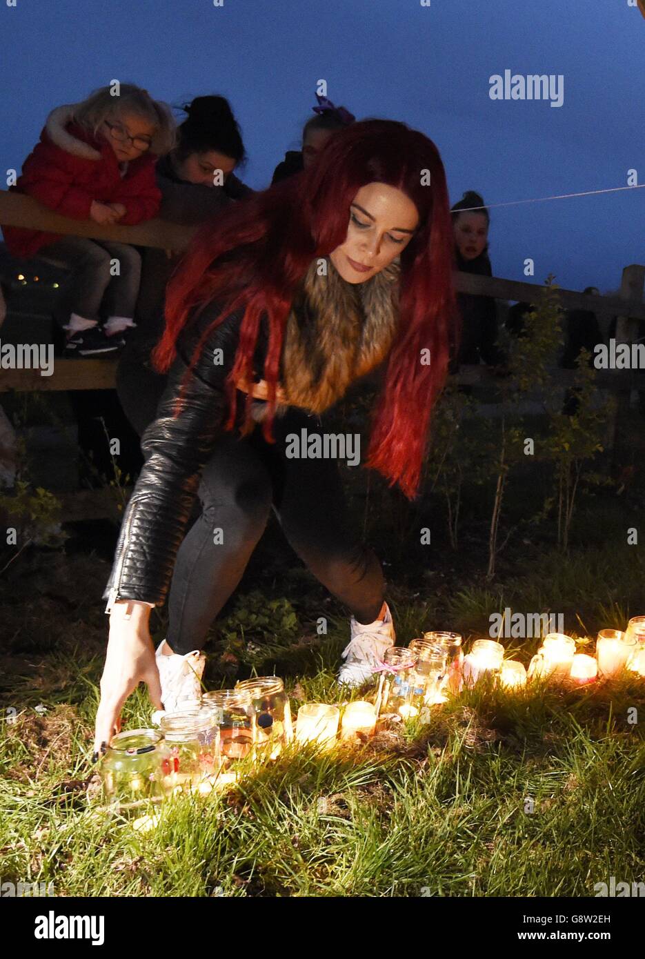 Une femme laisse une bougie à la mémoire de Summer Grant, jeune de sept ans, qui a été mortellement blessé lorsqu'un château rebondit alors qu'elle jouait dessus, lors d'une veillée aux chandelles au Harlow Town Park dans l'Essex. Banque D'Images