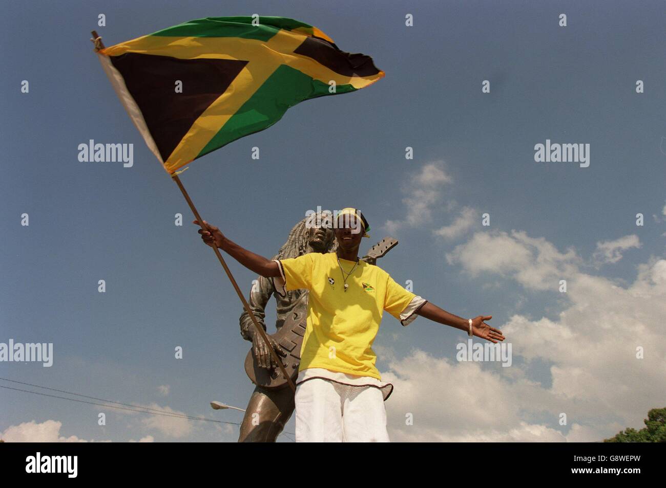 Un fan jamaïcain se tient devant une statue de Bob Marley Banque D'Images