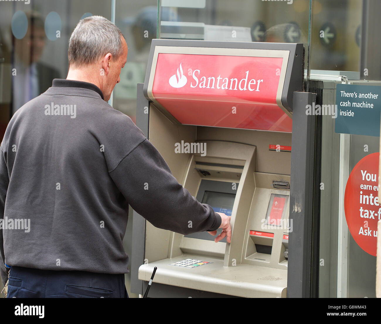 Un homme utilise une machine à billets à l'extérieur d'une succursale de Santander dans le centre de Londres, comme l'a déclaré la banque de grande rue la ruée vers le prêt avant l'augmentation des droits de timbre de ce mois-ci a aidé les bénéfices à augmenter de 13% car elle a bénéficié d'une poussée des prêts hypothécaires. Banque D'Images