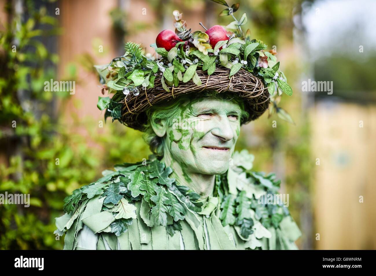 Un homme vêtu de feuilles regarde la danse traditionnelle de la maypole dans le puits de Chalice, Glastonbury, où les festivités de Beltane ont lieu le jour de mai. Banque D'Images