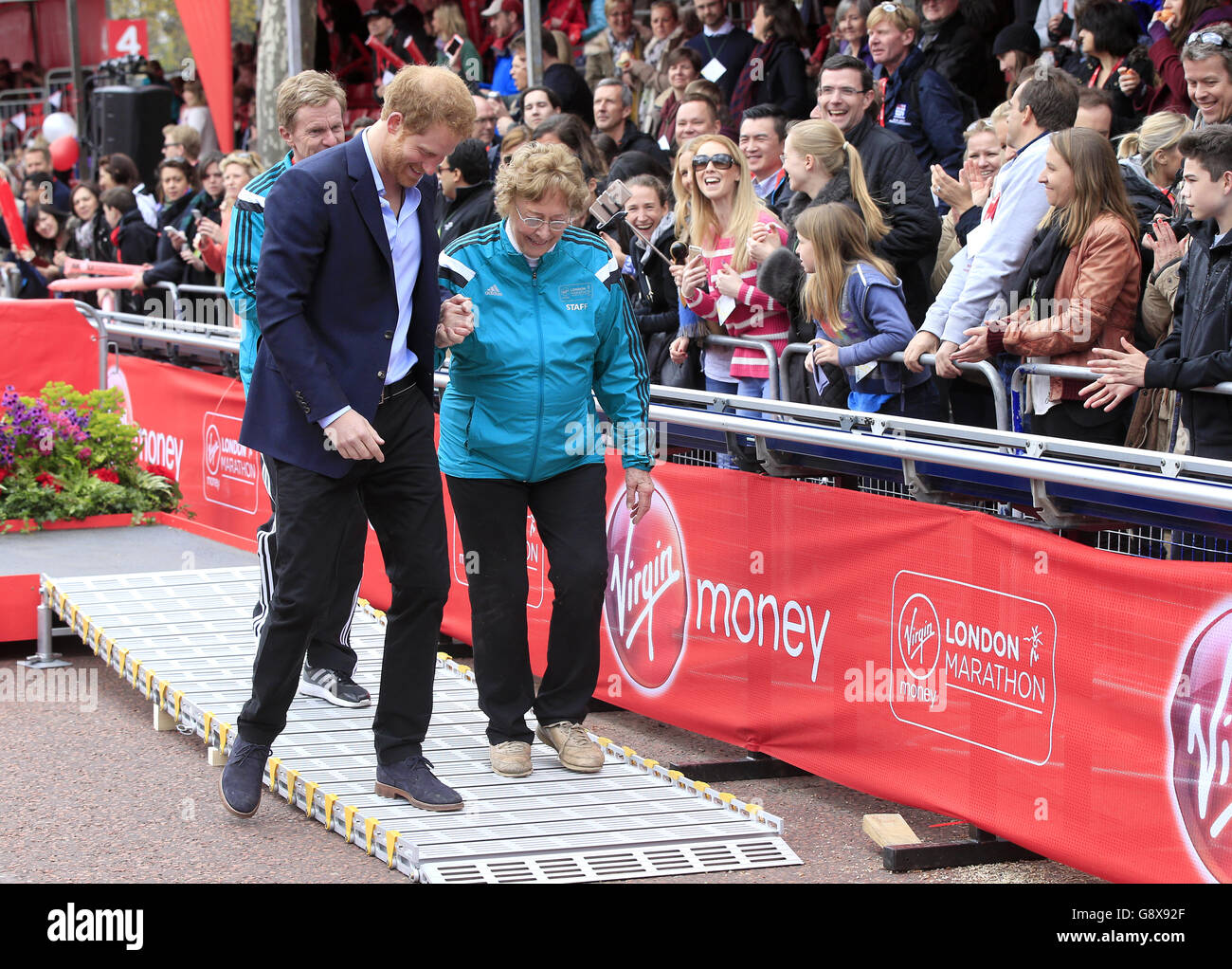 Le Prince Harry escorte la veuve du fondateur du London Marathon John Disley du podium lors du Virgin Money London Marathon de 2016. Banque D'Images