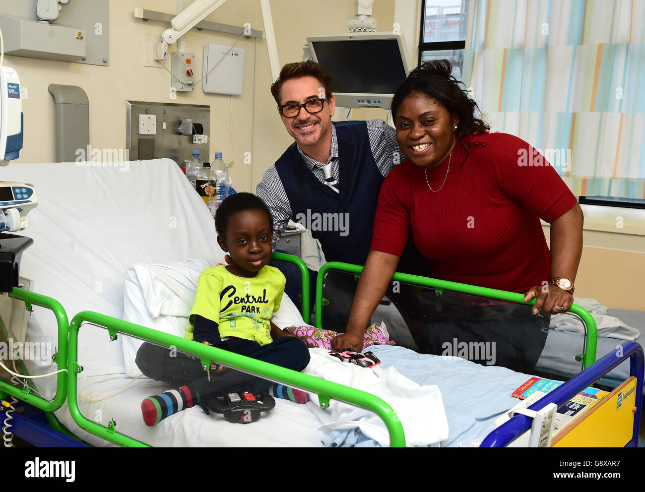 L'acteur d'Iron Man Robert Downey Jr (au centre) rencontre Michael (nom de famille non donné), âgé de 7 ans, d'Edmonton, lors d'une visite au Great Ormond Street Hospital (GOSH), à Londres, avant la première européenne de Captain America : Guerre civile à Londres le 26 avril, la star du film a passé l'après-midi à rendre visite aux patients et à leurs familles et à distribuer des friandises Captain America. Banque D'Images