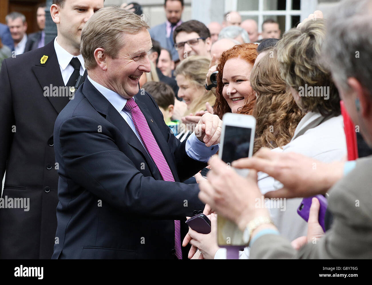 Taoiseach, nouvellement élu, Enda Kenny accueille les partisans alors qu'il quitte Leinster House, Dublin, pour aller à Aras an Uachtarain pour recevoir le sceau de la Taoiseach et le sceau du gouvernement. Banque D'Images