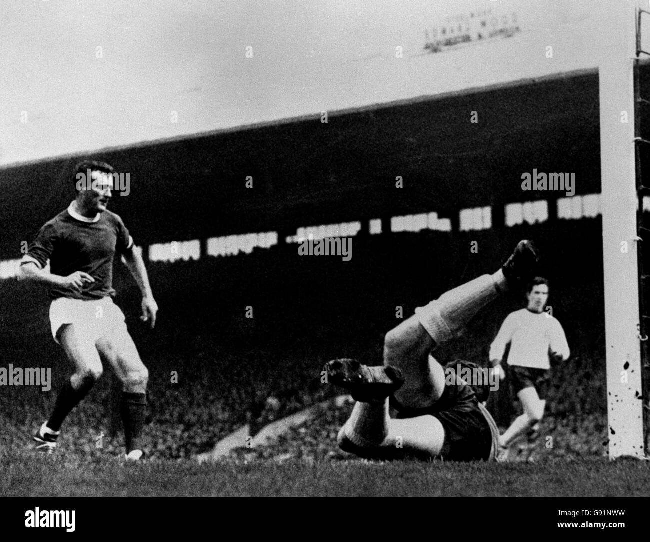 Tommy Lawrence, gardien de but de Liverpool, plonge à droite pour sauver un tir de Bobby Charlton (hors de vue) de Manchester United lors du match de la première division à Old Trafford.Noel Cantwell de United se précipite dans, à gauche, comme la balle est brouillée loin.United bat Liverpool 3-0. Banque D'Images