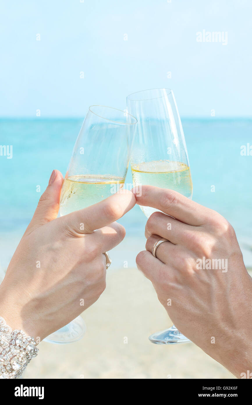 Des couples toasting with Wine mains, fond de ciel sable mer Banque D'Images