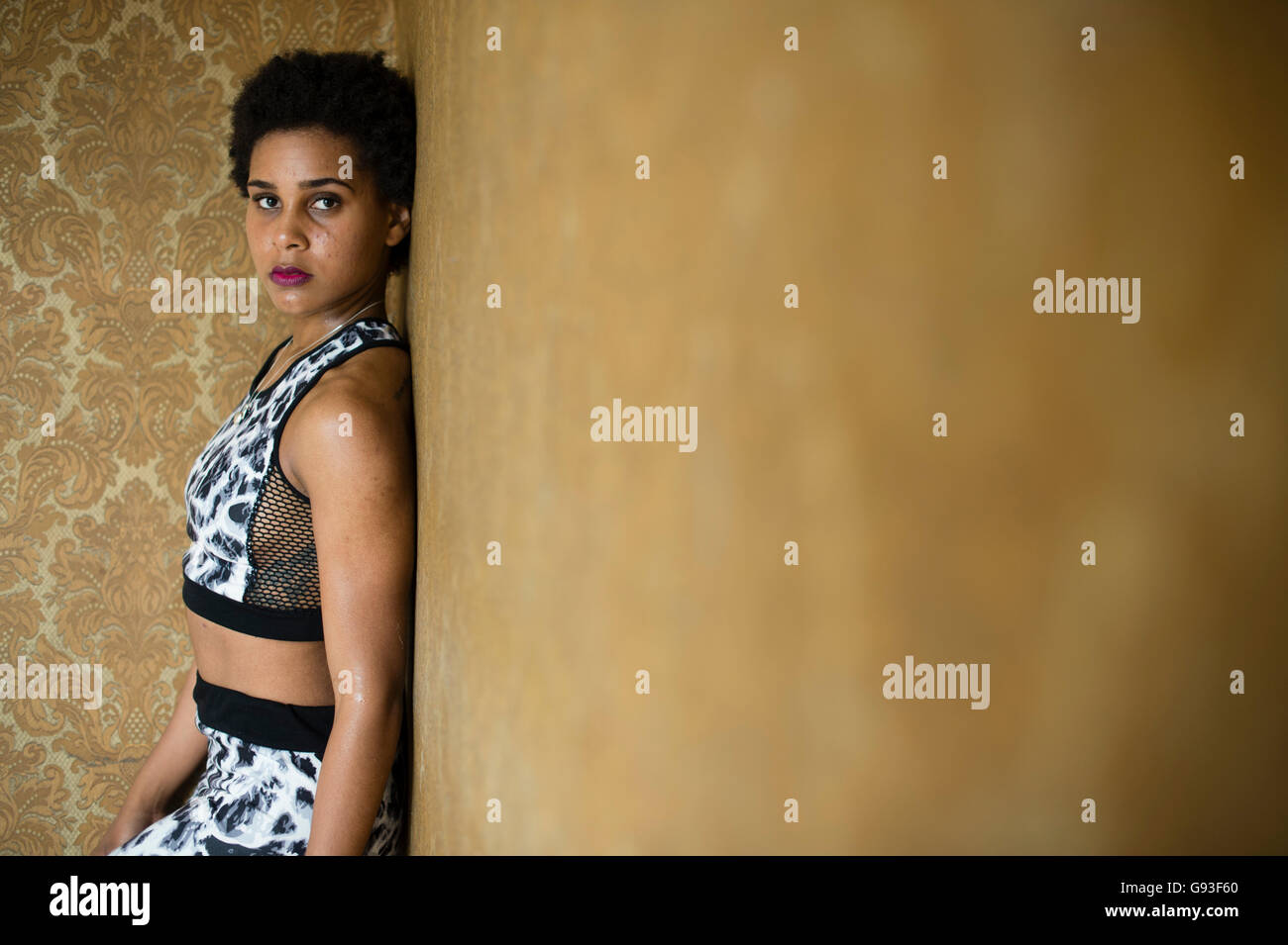 La beauté en déréliction : la photographie de mode d'une jeune afro-caraïbes femme fille seule dans un bâtiment abandonné à l'abandon de porter les vêtements de style de remise en forme, à la sensuelle et moody Banque D'Images