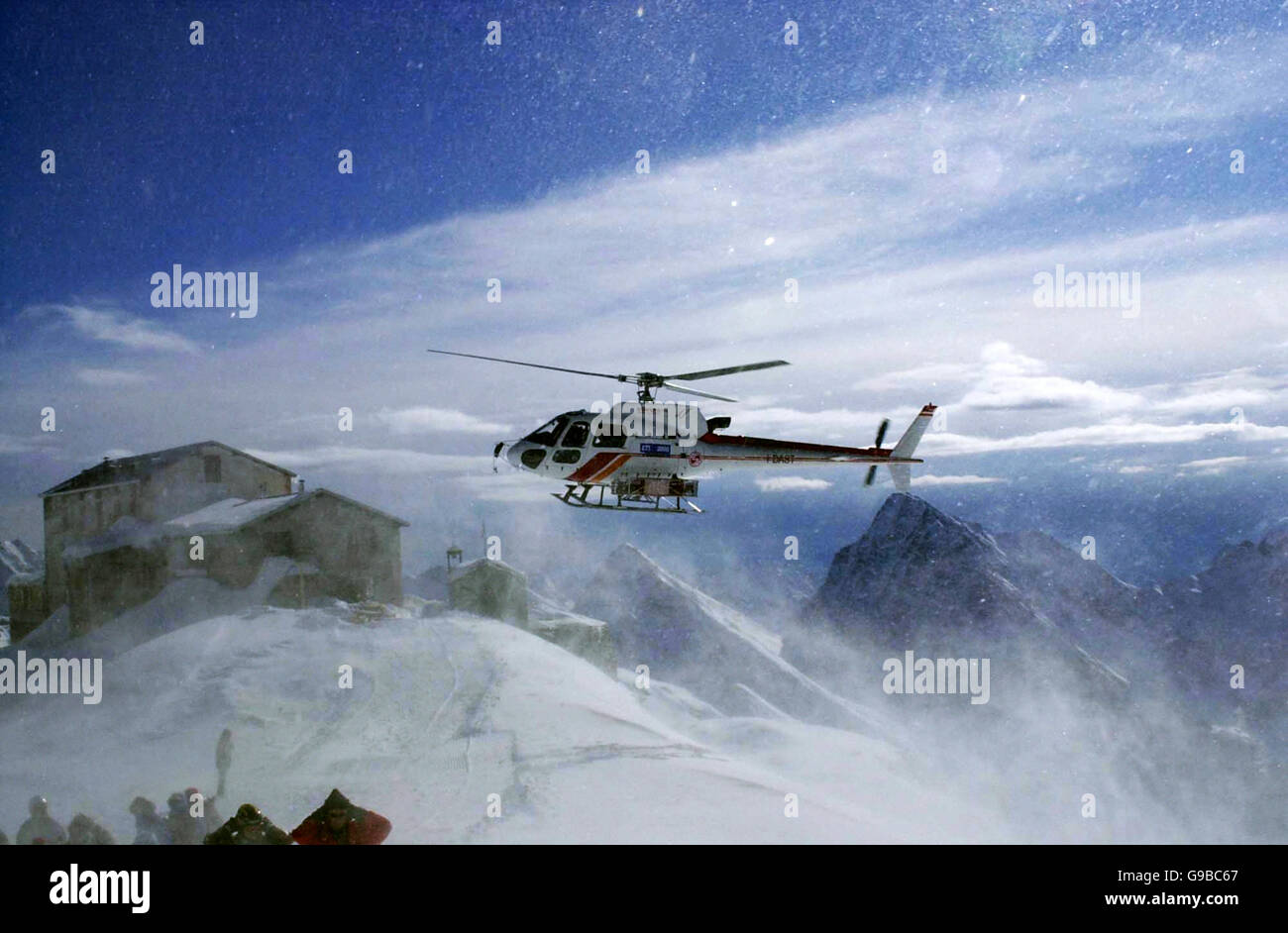 Les skieurs qui attendent l'héli-ski d'un avion Eurocopter AS-350B-3 Ecureuil, détournent leur tête du blizzard de neige causé par les pales de l'hélicoptère, à Alagna, dans le nord de l'Italie. Banque D'Images