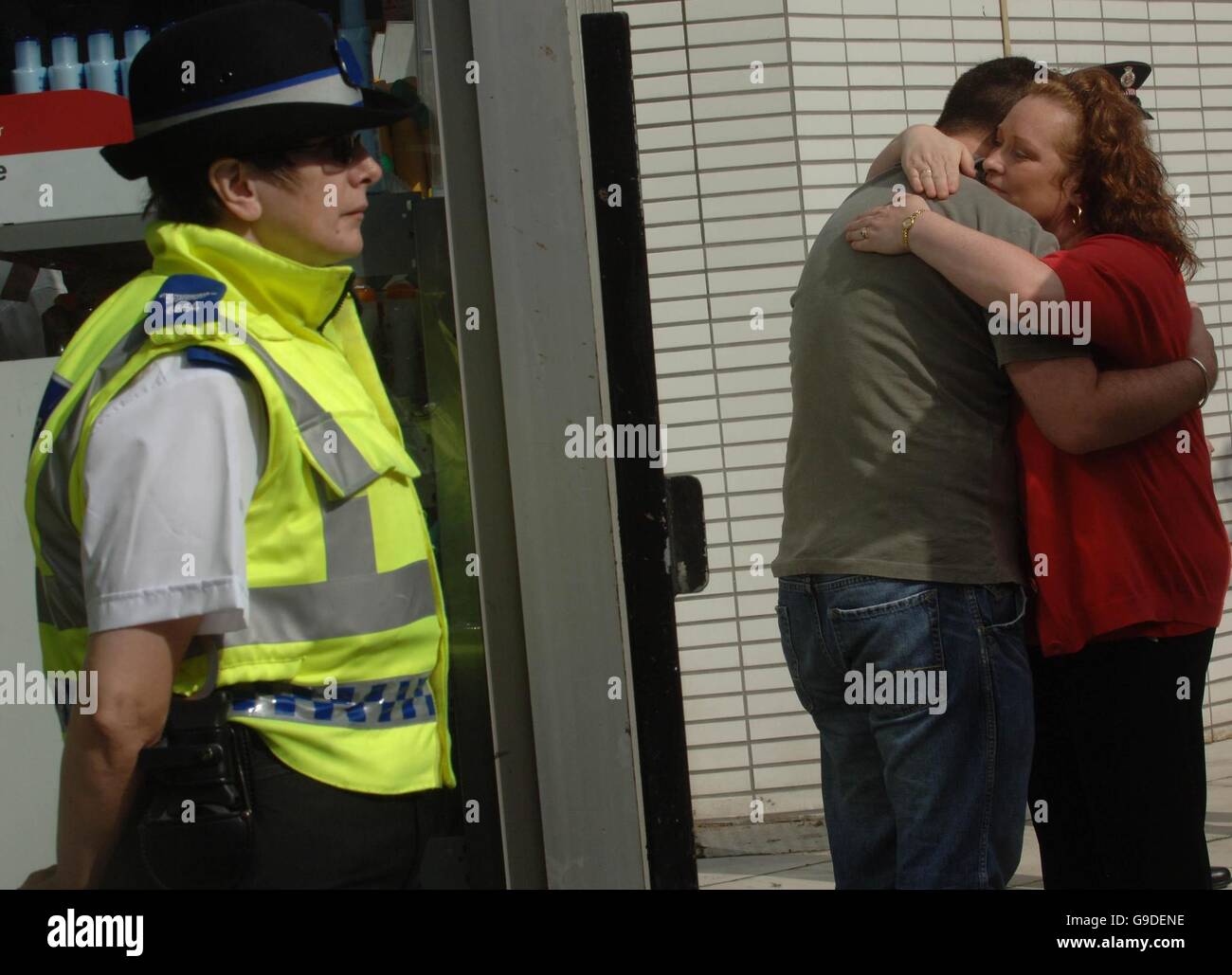 Deux personnes se réconfortant l'une l'autre comme un policier se tient À proximité de la gare King's Cross de Londres Banque D'Images