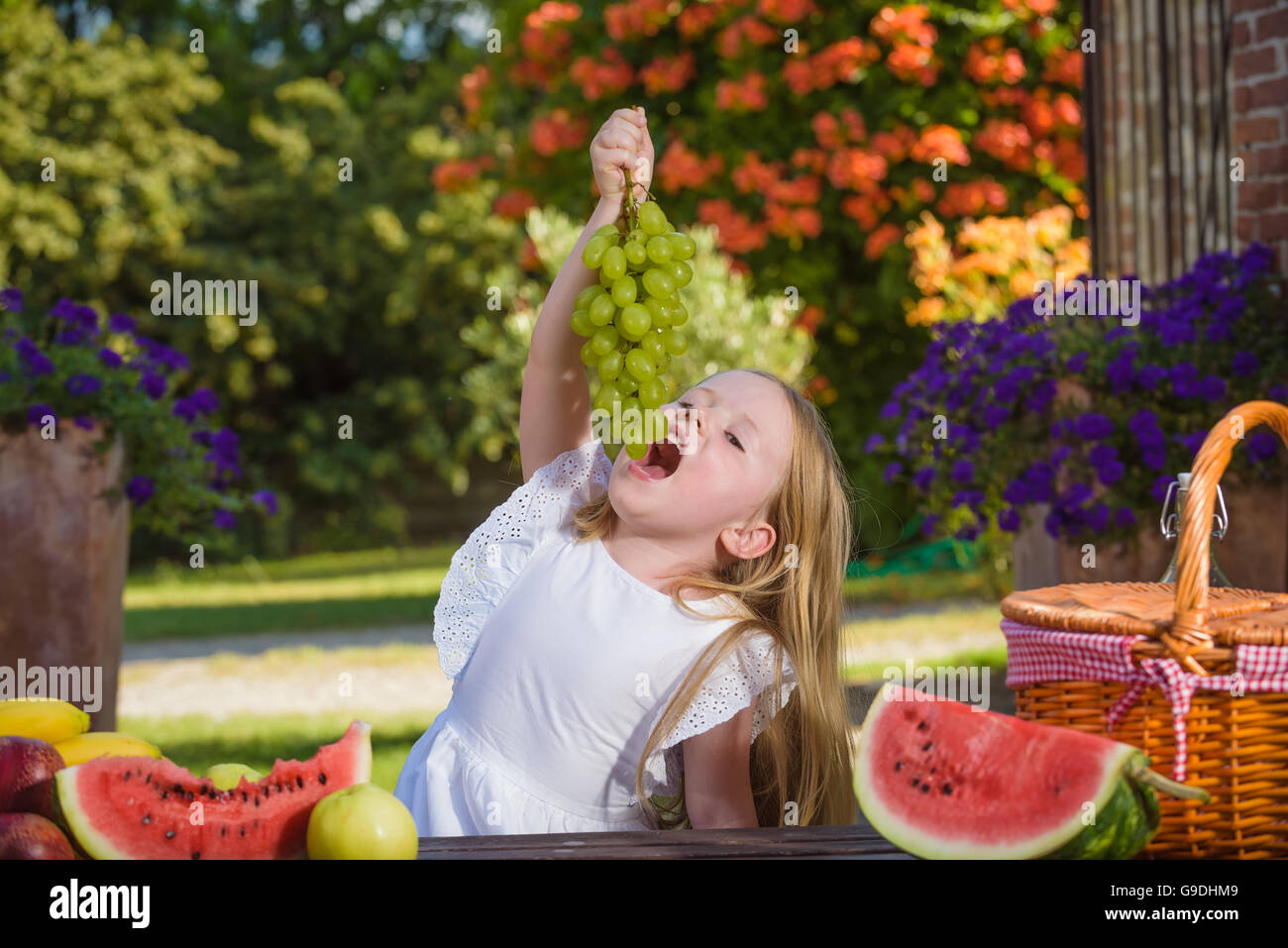 Beautiful happy little girl eating délicieux raisin vert. Banque D'Images