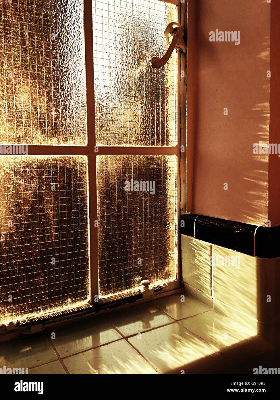 1920 'vintage' Galets verre fil de poulet dans le cadre de la fenêtre à battants en vert salle de bains carrelée, NYC, USA Banque D'Images