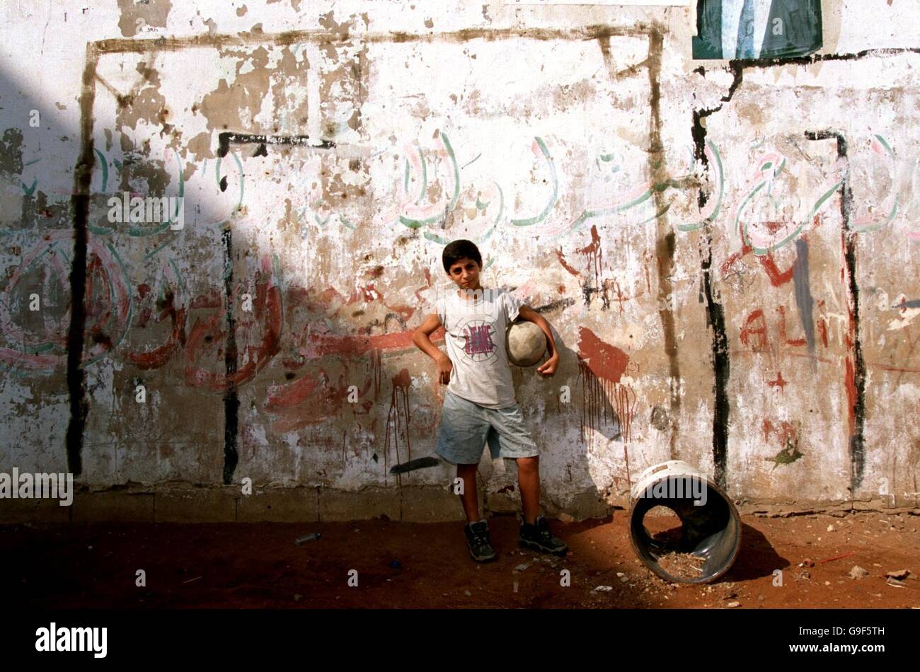 Un garçon libanais tient un ballon de football devant ses postes de but dans le camp de réfugiés de Chattila, Beyrouth, Liban.Le camp contient des Palestiniens et des Libanais qui vivent maintenant dans la région que les chrétiens Falangistes ont massacrée en septembre 1982. Banque D'Images
