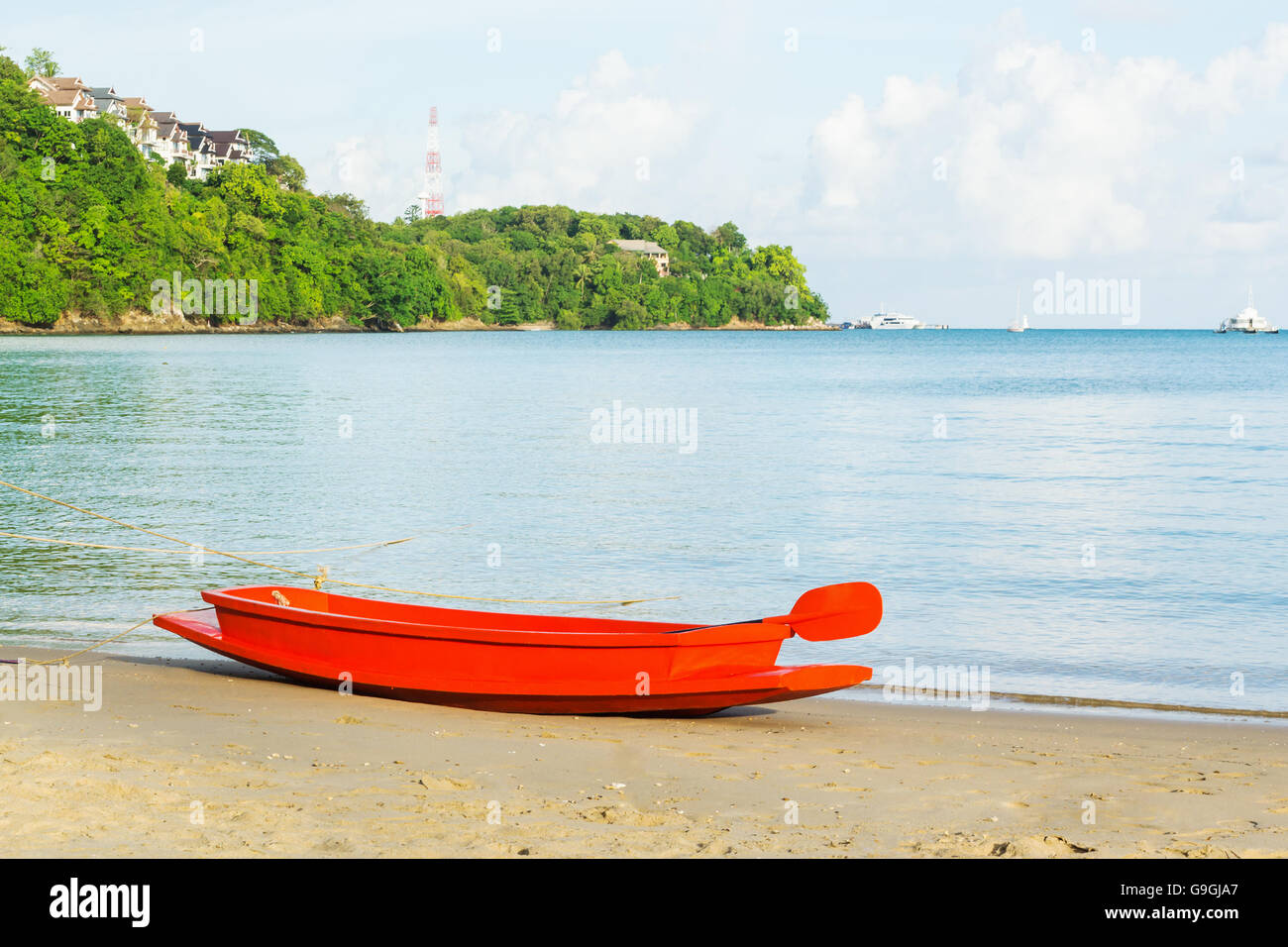 Bateau orange sur la plage de sable avec la mer bleu et le fond de ciel dans la lumière du soir Banque D'Images