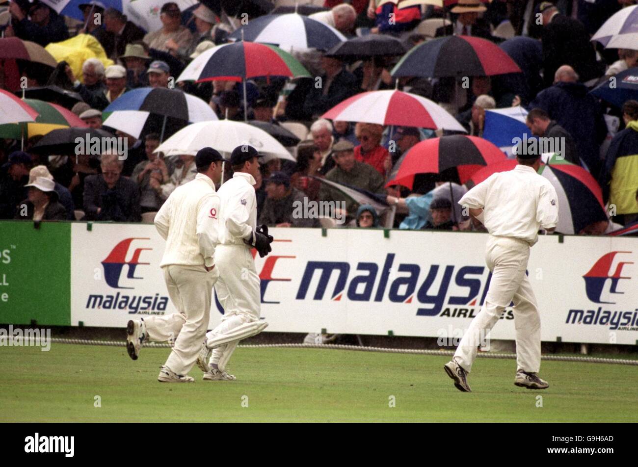 (G-D) Graham Thorpe, Alec Stewart et Michael Atherton, en Angleterre, descendent du terrain quand la pluie tombe Banque D'Images