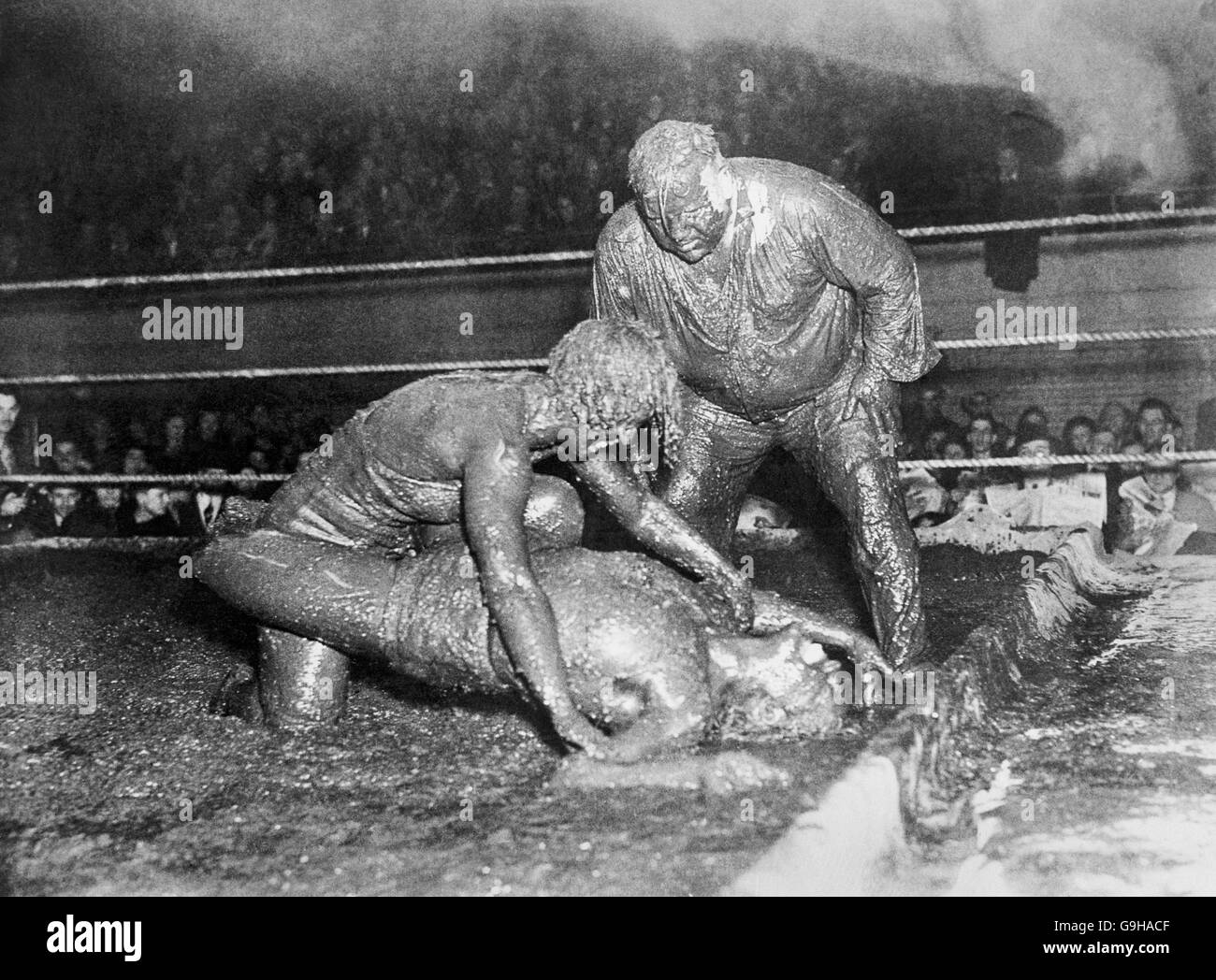 Mildred (Cyclone) Burke de Kansas City, Missouri, prestataire au championnat du monde de lutte des femmes, et Leona (Babe) Gordon de Chicago se sont donné un «traitement» de sac de boue lorsqu'ils ont pris part à un match de lutte de style hindou dans un anneau rempli de boue à Akron, Ohio. Images: Mildred (Cyclone) Burke (en haut) épingler son adversaire tout aussi boueux, Leona (Babe) Gordon, dans le désordre visqueux comme Ernie Maddock, l'arbitre, se rapproche de taper Miss Burke sur l'épaule pour la déclarer la gagnante. L'arbitre semble avoir recueilli autant de boue que les combattants! Banque D'Images