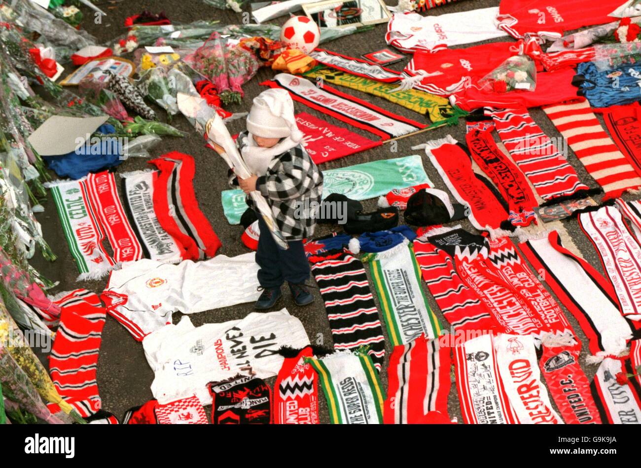 Un petit garçon se fraye un chemin à travers les hommages rendus à Old Trafford en l'honneur du légendaire directeur de Manchester United Sir Matt Busby, décédé aujourd'hui à l'âge de 85 ans, pour placer un bouquet de fleurs aux côtés de milliers d'autres Banque D'Images