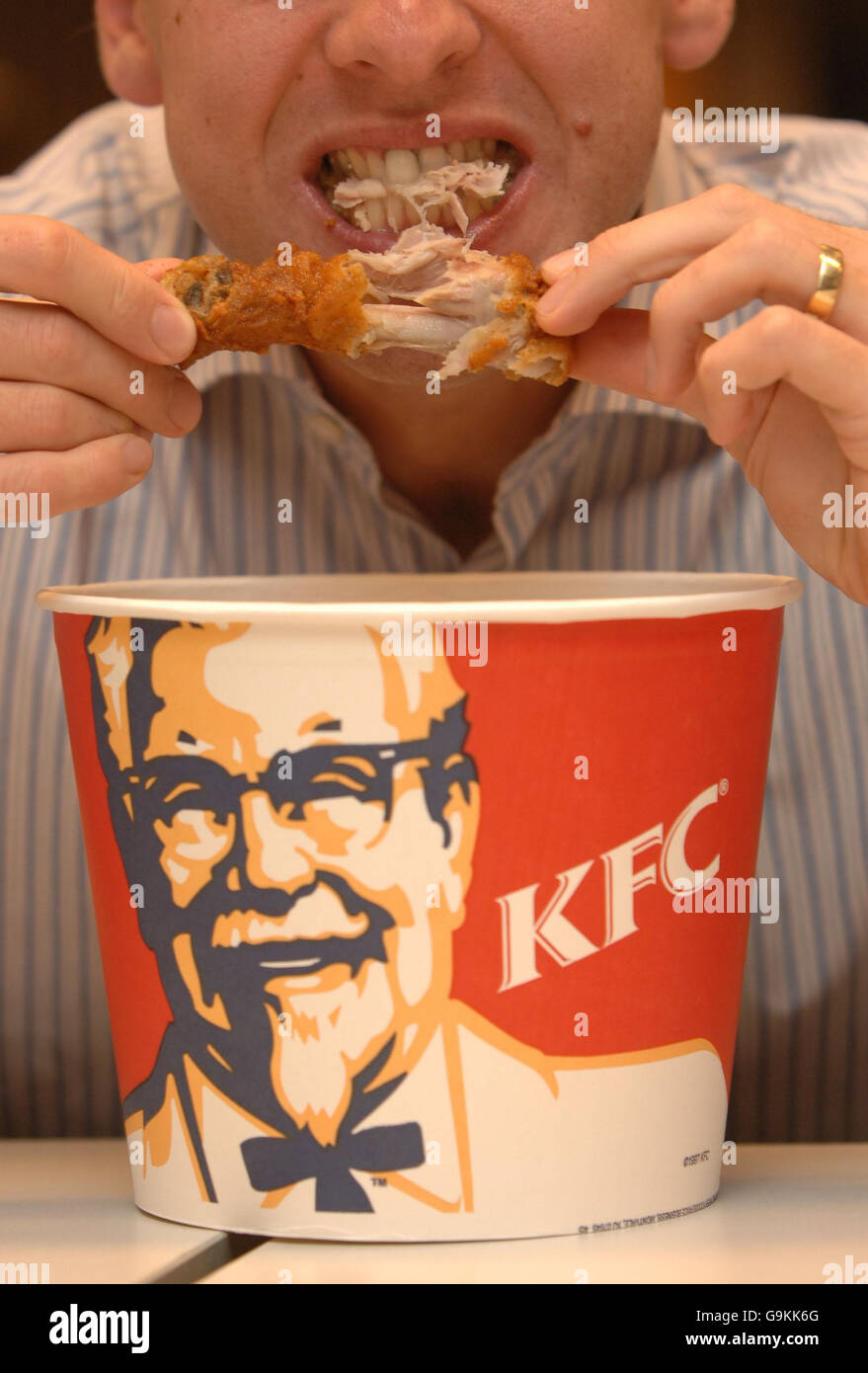 Un homme mange un morceau de poulet de la chaîne de restauration rapide KFC dans le centre de Londres. Banque D'Images