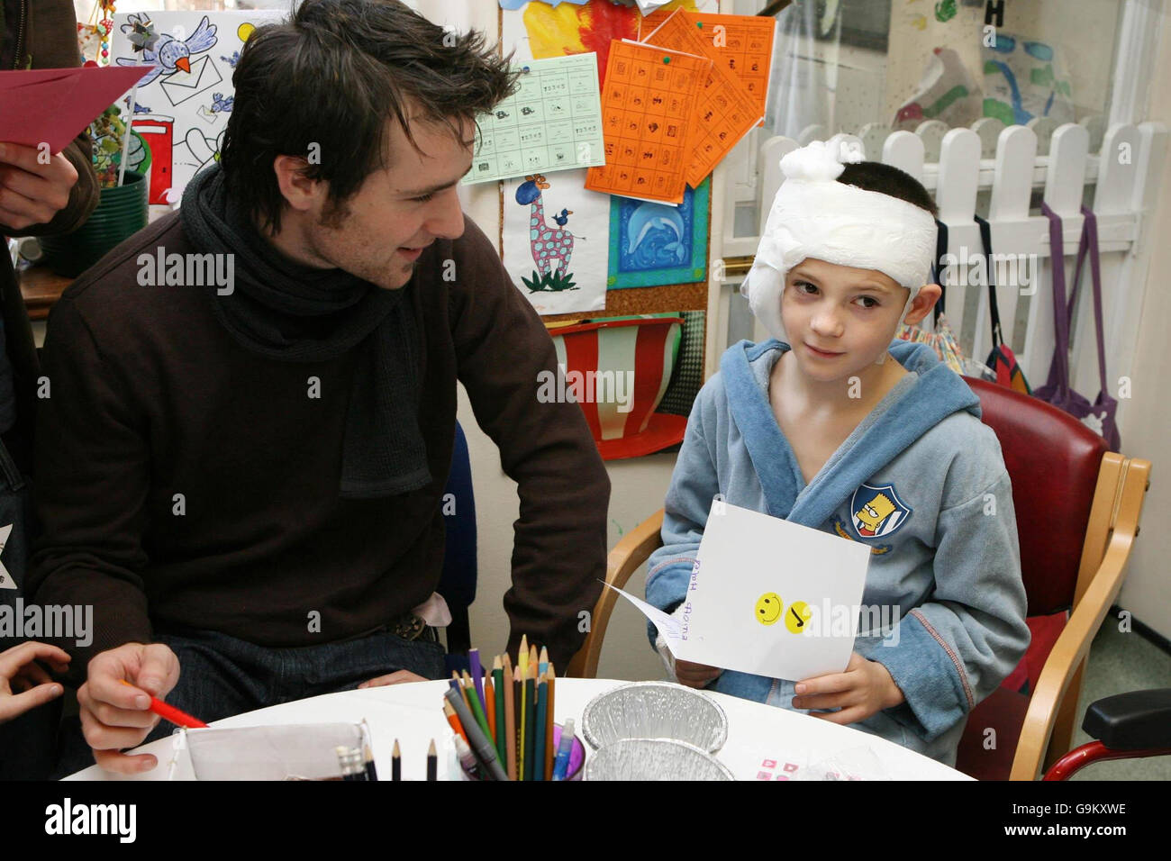 Harry Judd, du groupe pop McFly, crée une carte de Noël avec Elliott Hales, 9 ans, de Milton Keynes, lorsqu'il visite l'hôpital pour enfants de Great Ormond Street avec ses camarades de bande. Banque D'Images