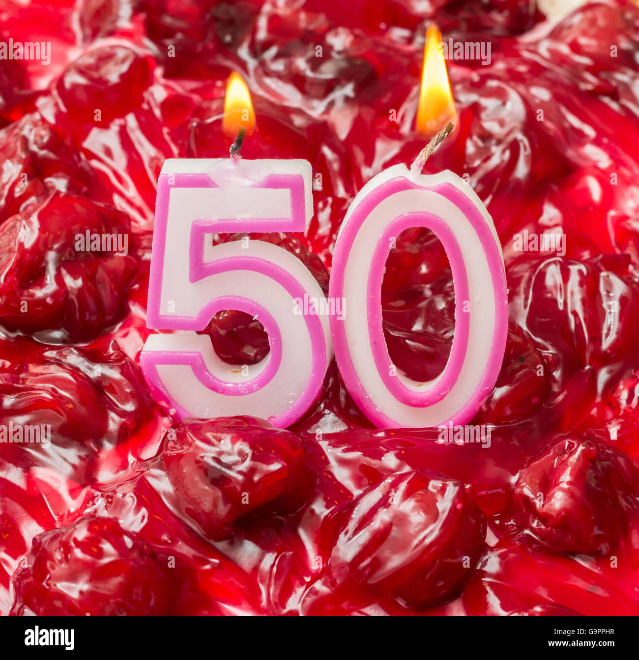 Cheese cake cerise avec des bougies allumées pour 50e anniversaire Banque D'Images