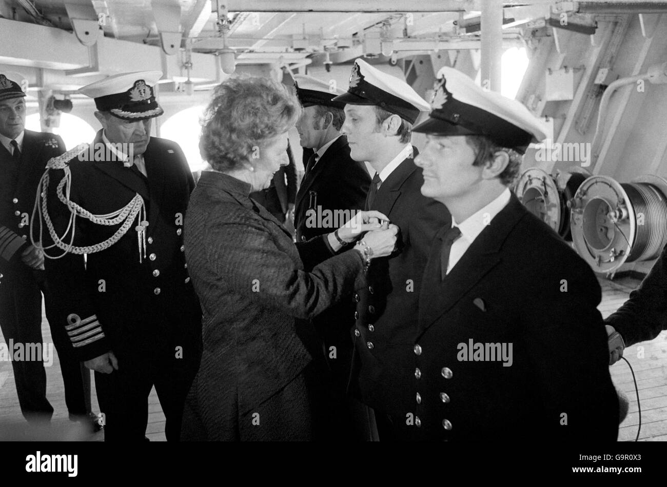 La première ministre Margaret Thatcher, qui a passé 80 minutes à bord du HMS Hermes, alors qu’elle naviguait jusqu’à Portsmouth, fixe une longue médaille de service sur la poitrine d’un officier, tandis que le capitaine Lynn Middleton regarde. Banque D'Images